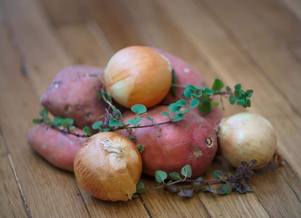 Sweet potatoes, onions, and oregano on a table