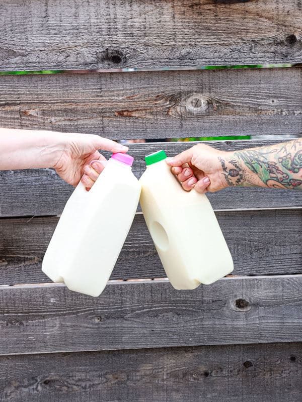 Two arms holding milk jug quarts