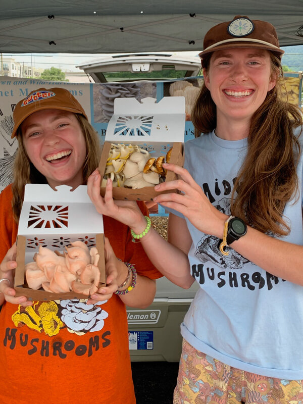 Midway Mushroom vendors holding boxes of mushrooms